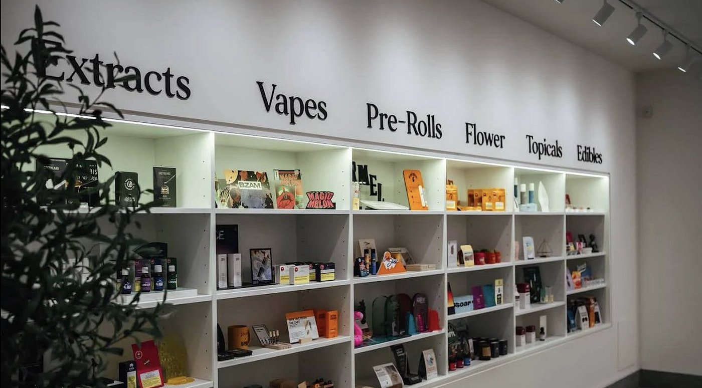 THCancun Dispensary Smokeshop — white gallery shelves under strip lights with serif wall lettering